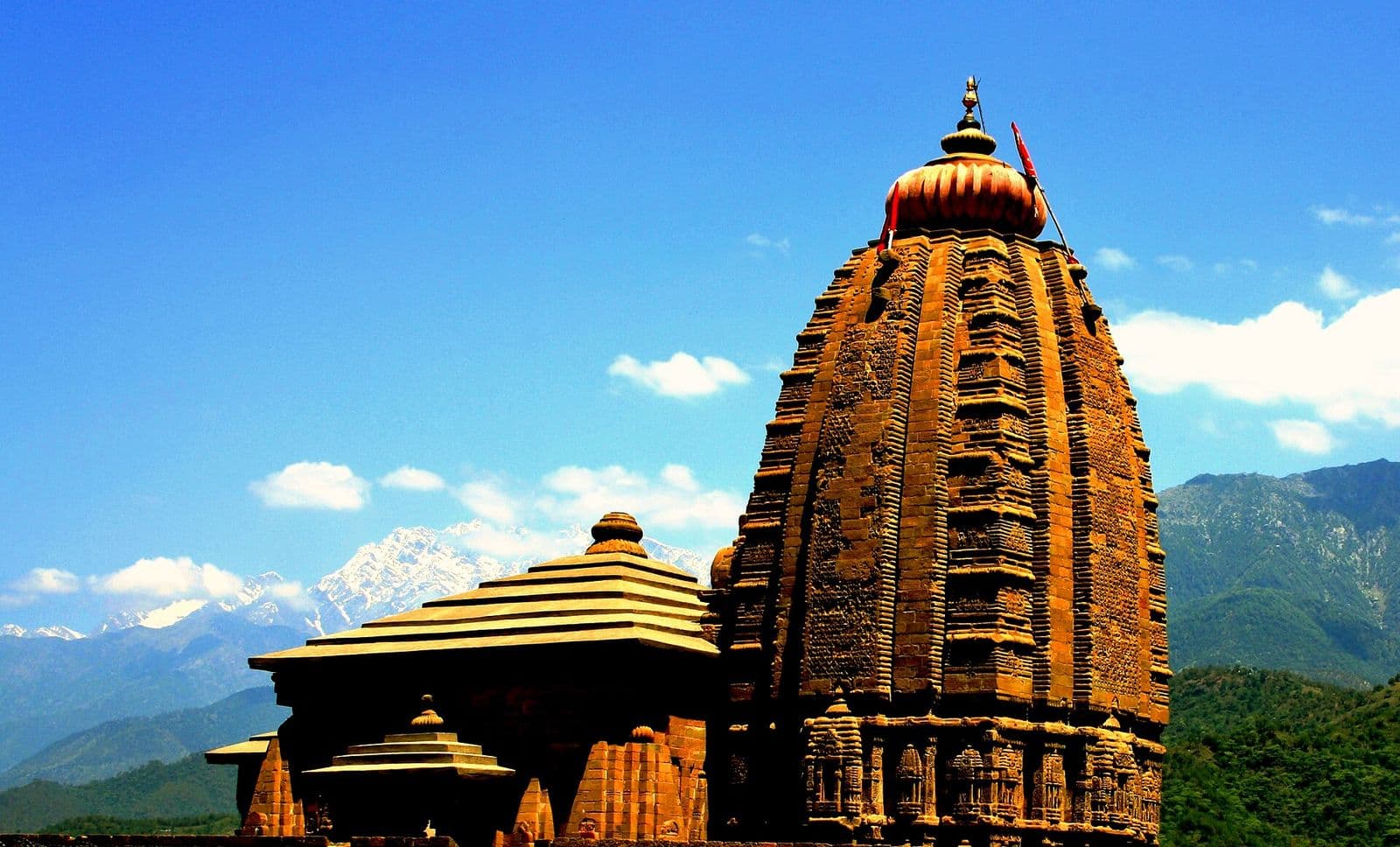Carved stone shikhara of the Baijnath Shiva temple with the snowy Dhauladhar range behind