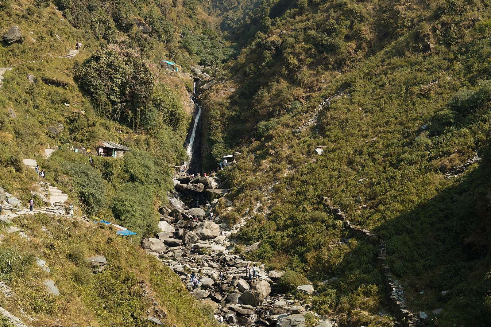 Bhagsu Waterfall plunging down a green, boulder-strewn gorge above Bhagsunag village near McLeod Ganj