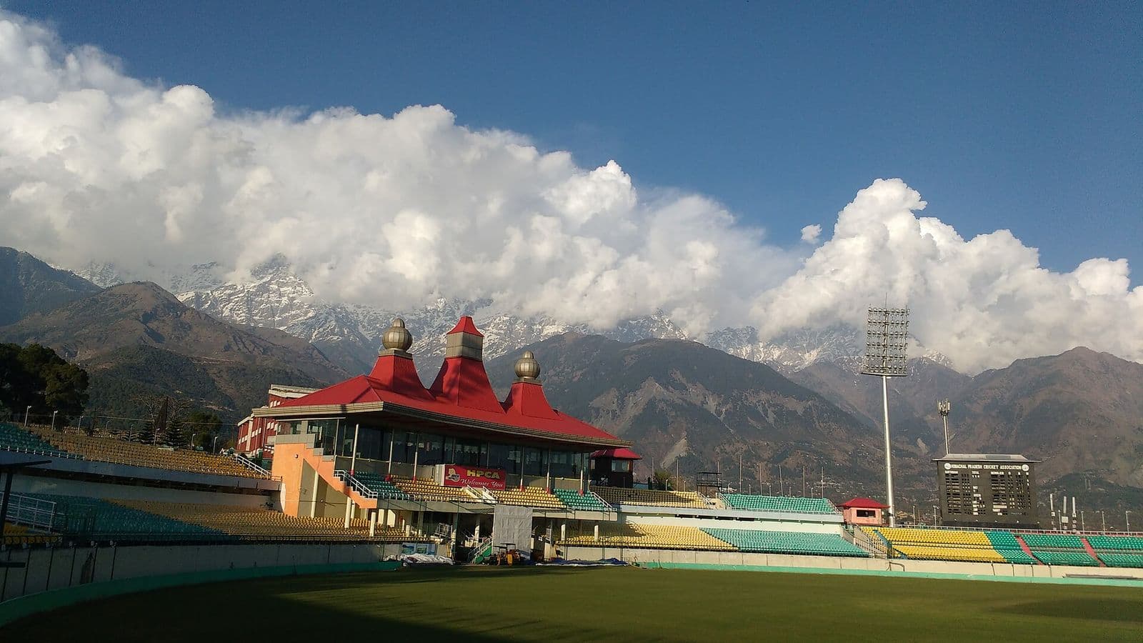 HPCA Cricket Stadium in Dharamshala with its red-roofed pavilion and the snow-capped Dhauladhar range behind