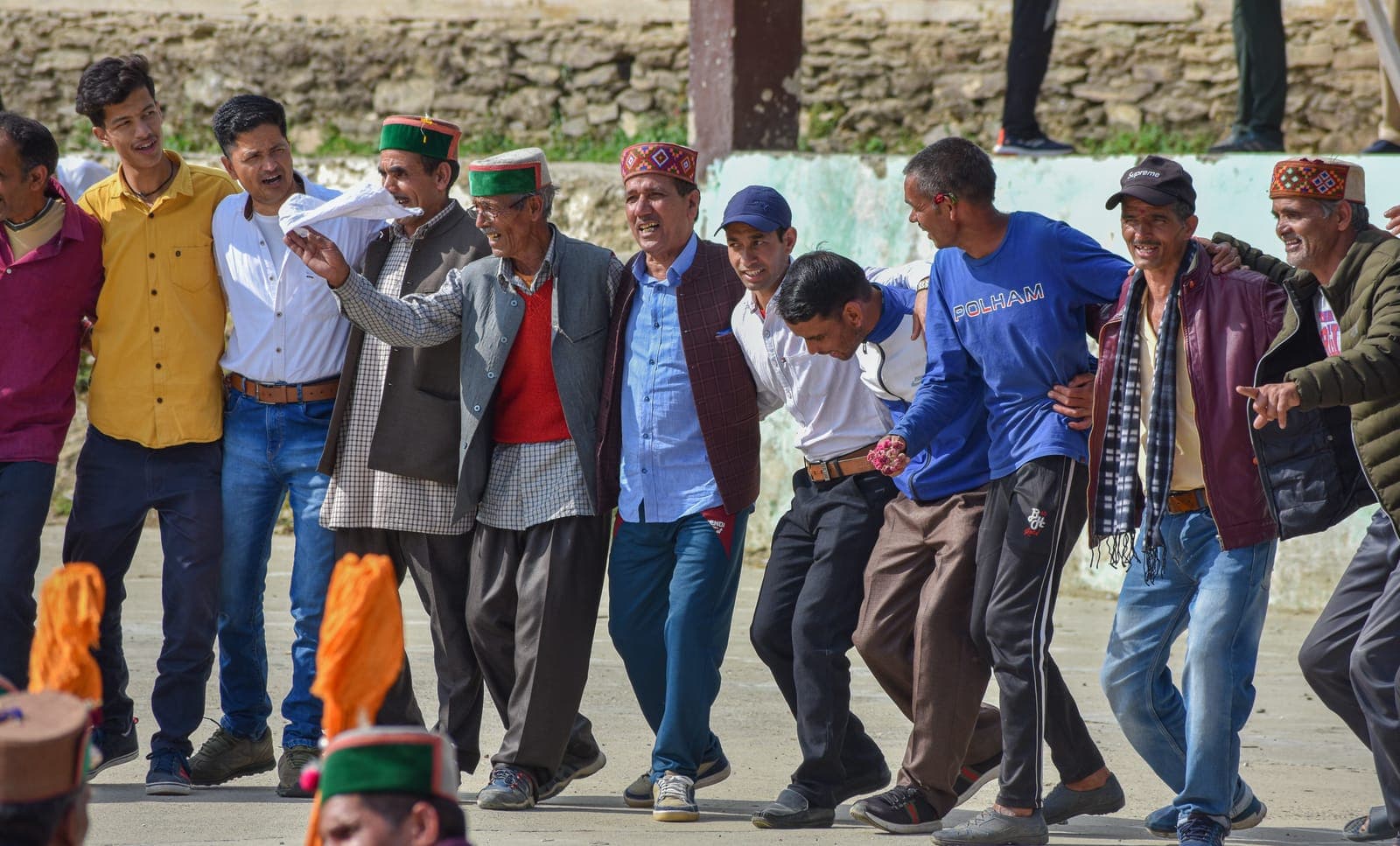 Men in Himachali caps dancing the nati in a line at a village fair in Kullu, Himachal Pradesh