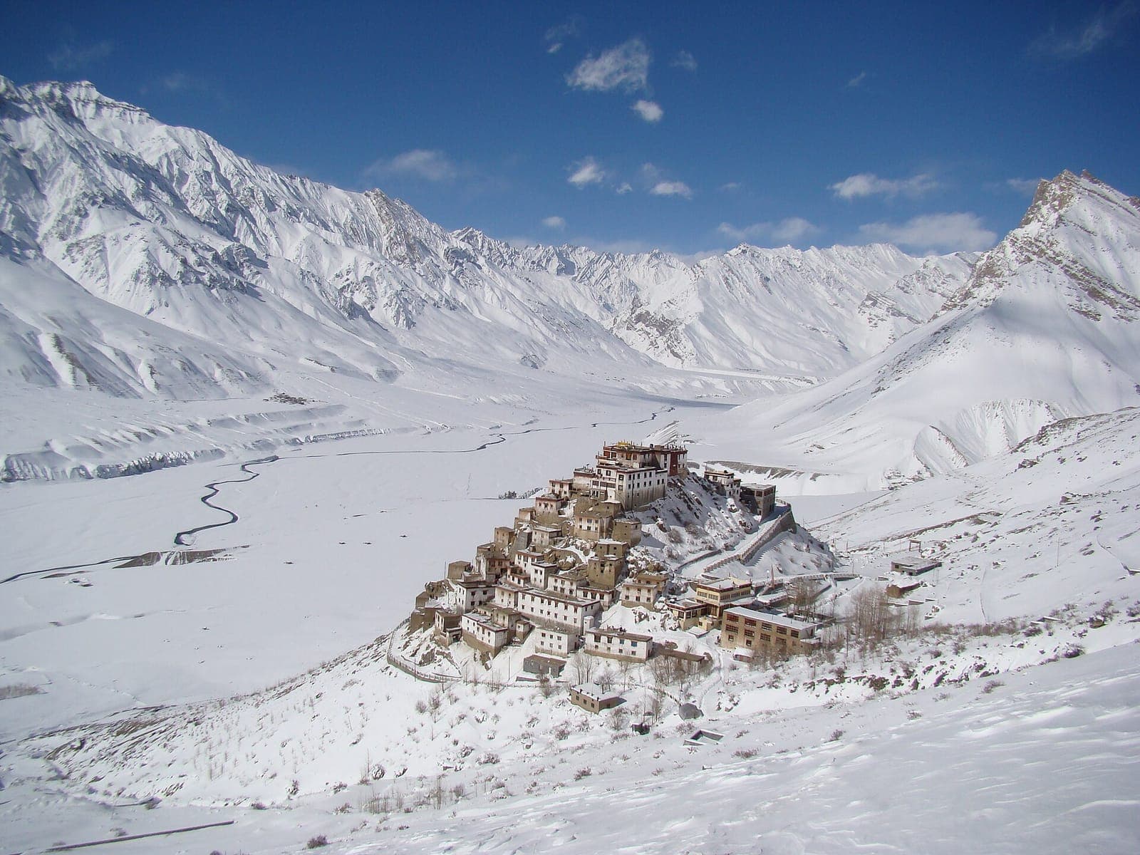 Key Monastery on its hilltop above the snow-covered Spiti valley in winter, with white mountains and blue sky