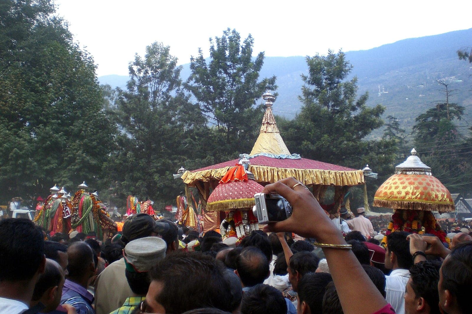Decorated palanquins of village deities carried through the crowd in the main procession of Kullu Dussehra
