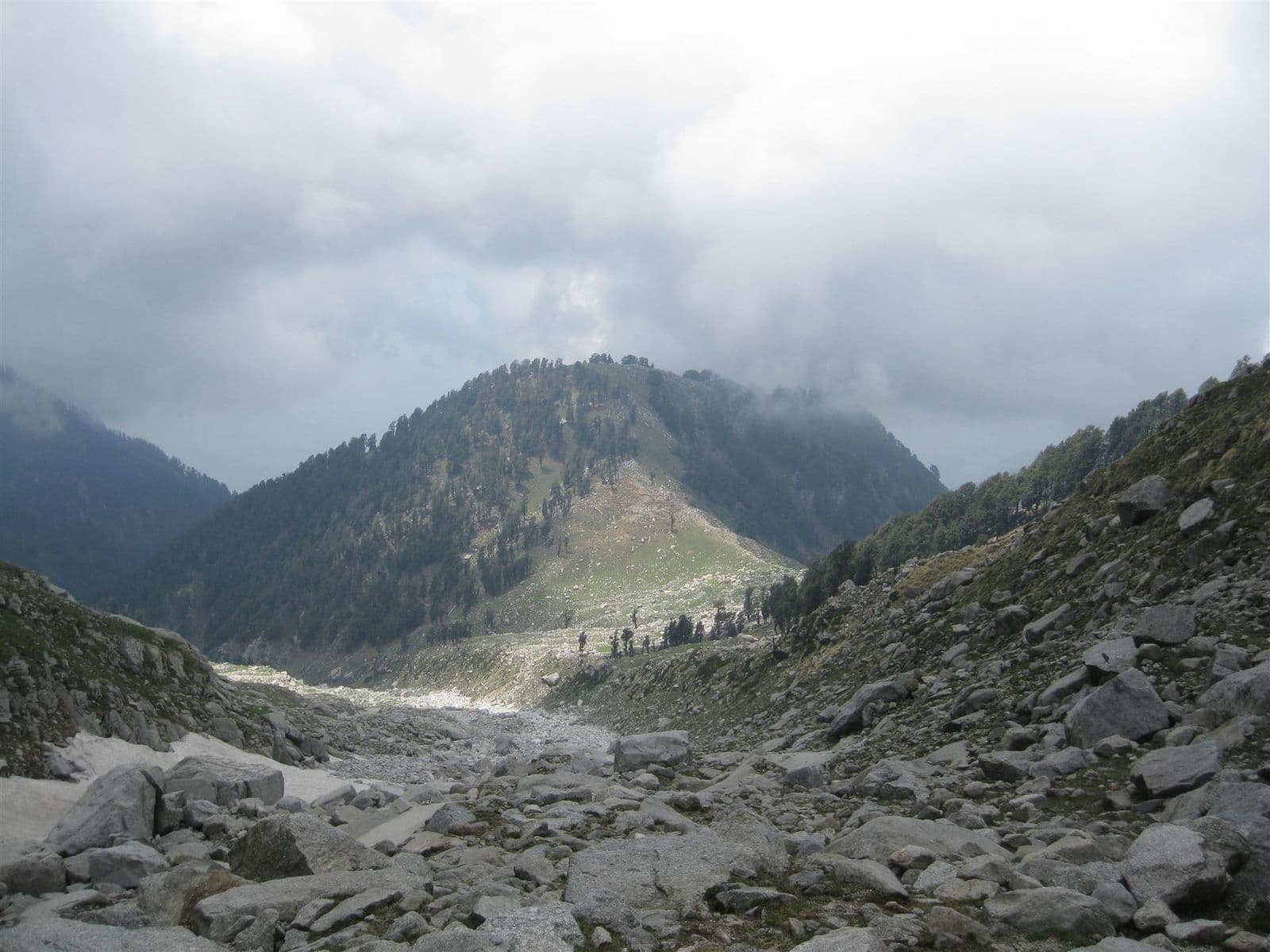 Boulder field and lingering snow at Laka Got below the Indrahar Pass, looking back down towards the forested ridge above Triund
