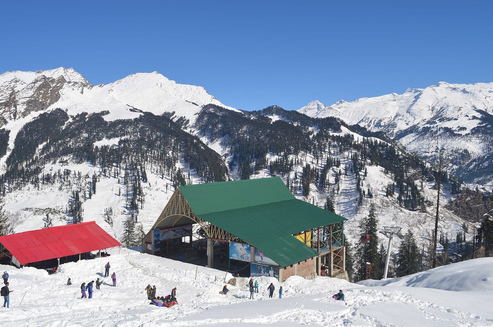Solang Valley ropeway station in deep snow with visitors and snow-covered peaks above Manali