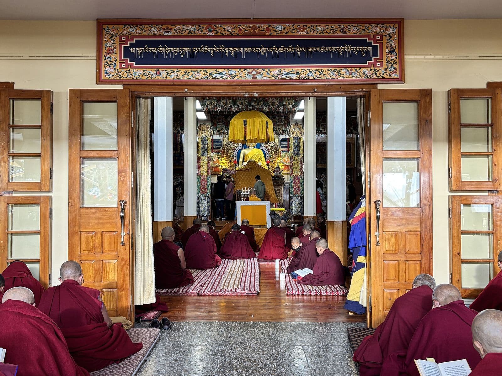 Tibetan Buddhist monks in maroon robes chanting prayers in Namgyal Monastery, McLeod Ganj