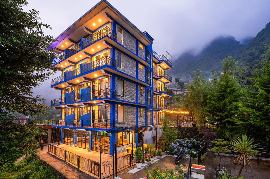 Shalom Backpackers building lit at dusk on the Upper Dharamkot hillside