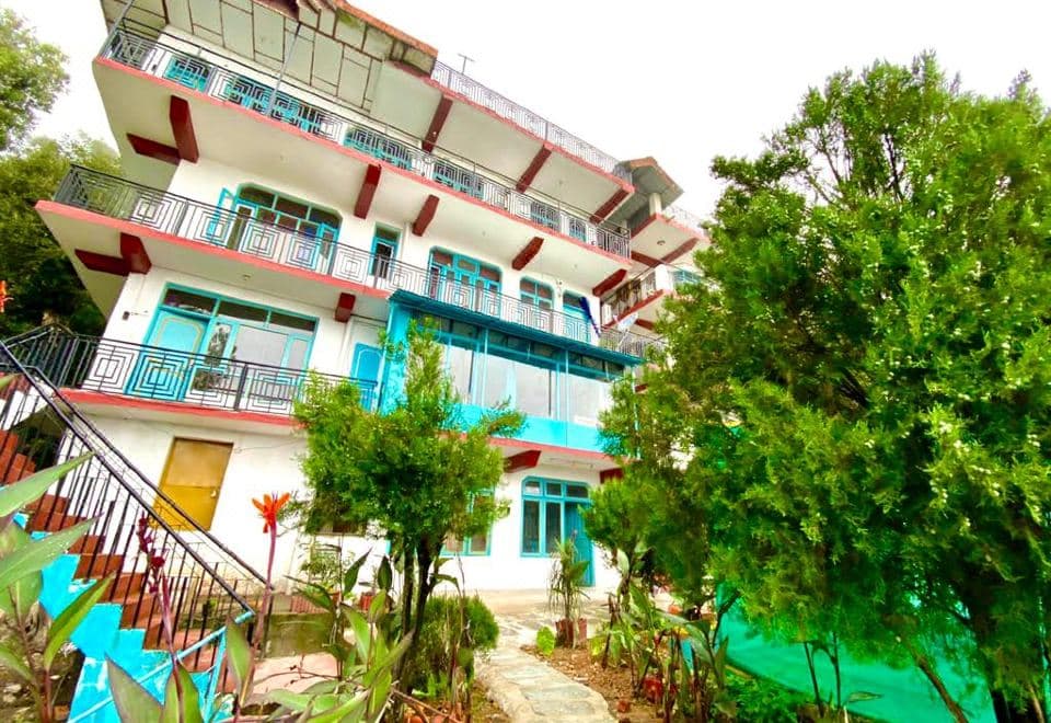 Albela House Hotel, a white building with red and teal balconies off Shivam Marg, McLeod Ganj