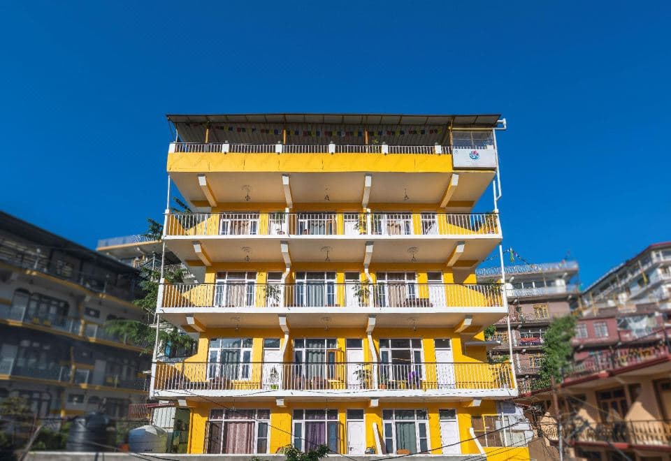 Yellow-and-white front of The Bougainvillea with balconies on every floor, Jogiwara Road, McLeod Ganj