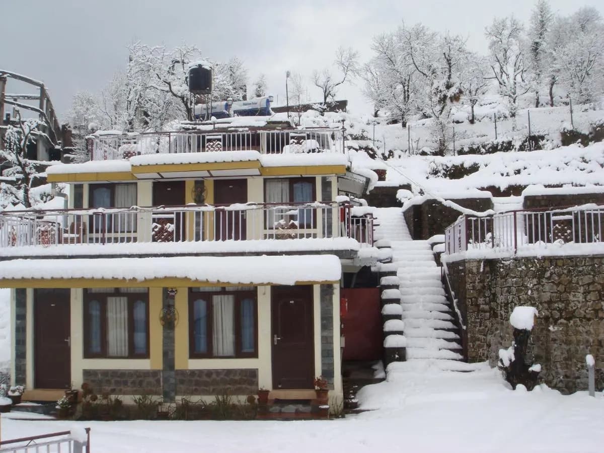 Snow-covered cottages and steps at Dragon I Resorts, Naddi