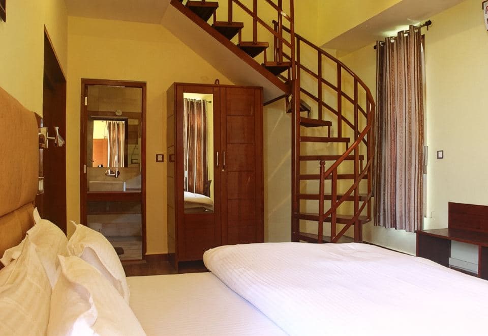 Attic room at The Sojourn with a double bed, wooden wardrobe and spiral staircase