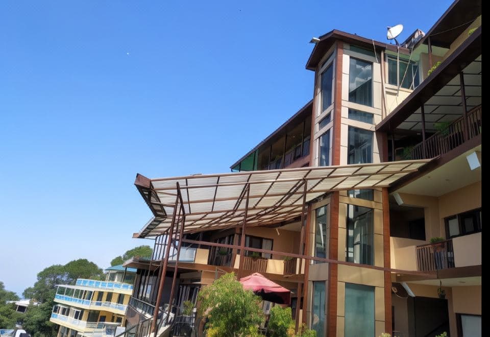 Hotel Norbu House, a glass-fronted building with balconies on the ridge facing the Dalai Lama Temple, McLeod Ganj