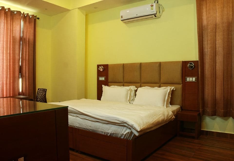 Deluxe room at The Sojourn with a double bed, padded headboard and desk