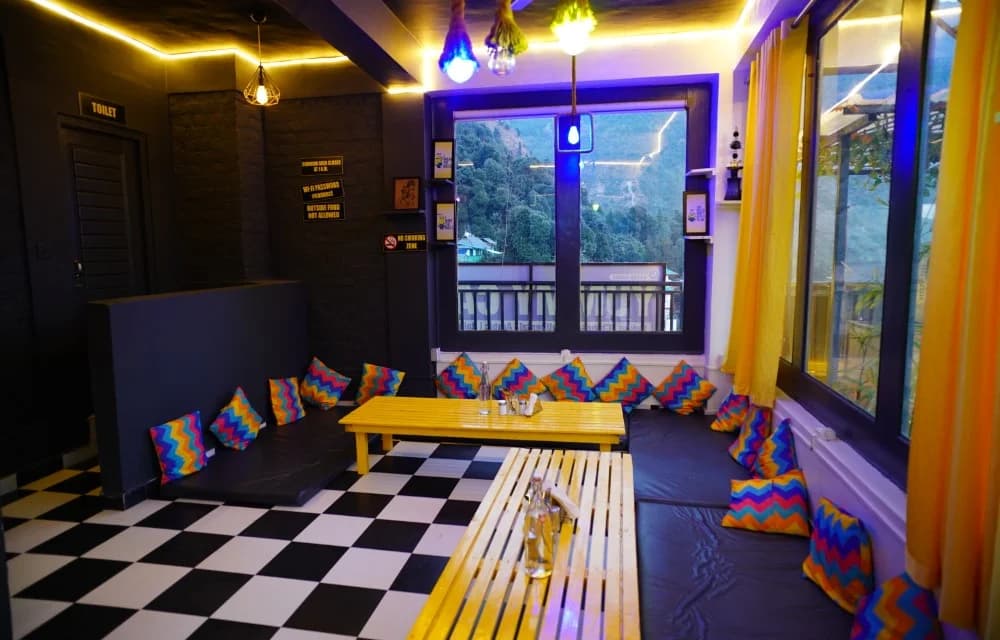 Lounge with low benches, colourful floor cushions and a large window looking out over the wooded valley