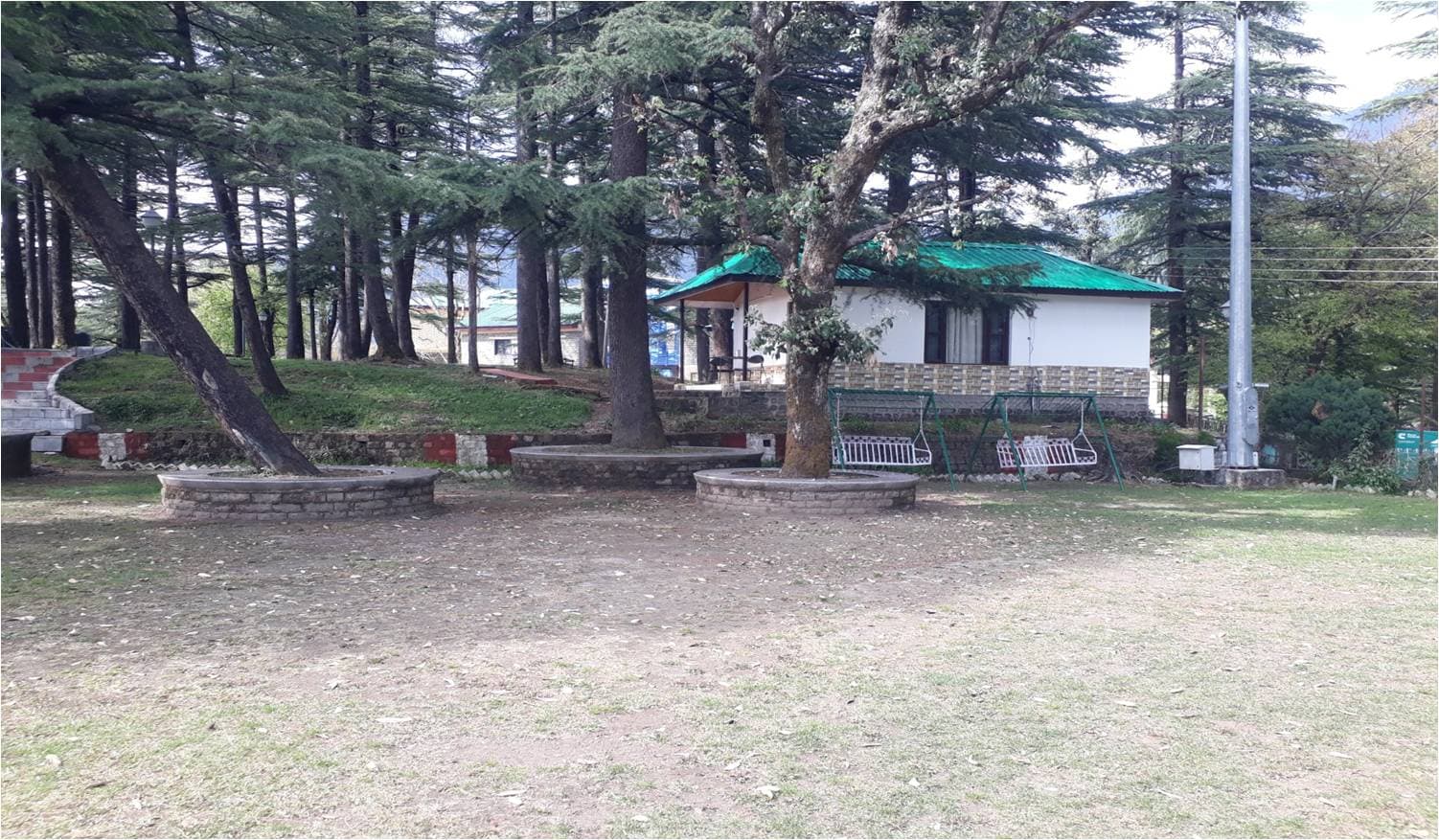 Lawns, deodar trees and garden huts at HPTDC Hotel Bhagsu, McLeod Ganj