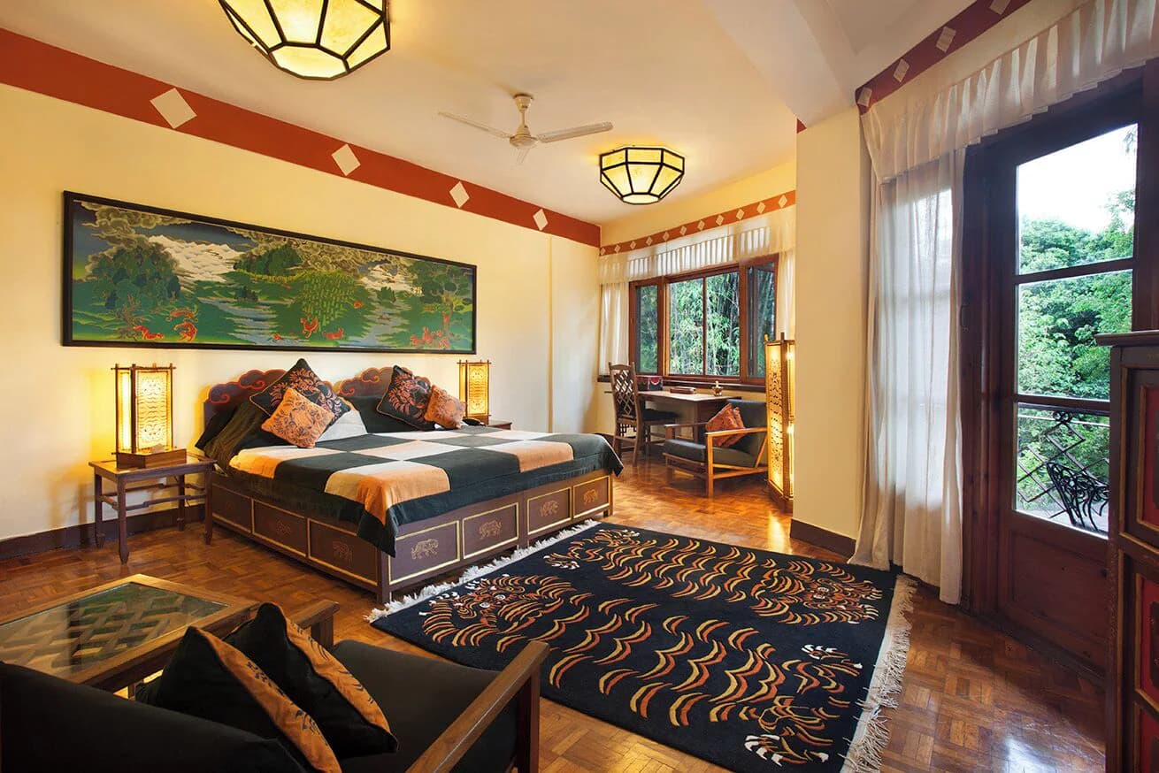 Guest room with Tibetan painting and wooden furniture at Norling House, Norbulingka