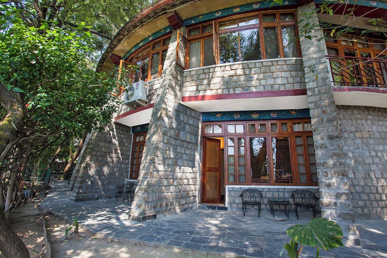 Stone building with balcony and outdoor seating at Norling House, Norbulingka
