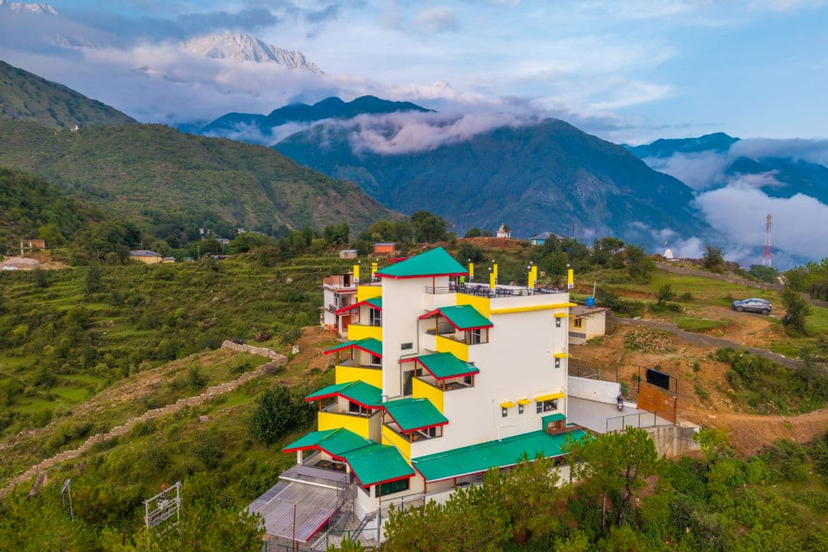 Colourful The Hosteller Dharamshala building set among terraced fields and mountains