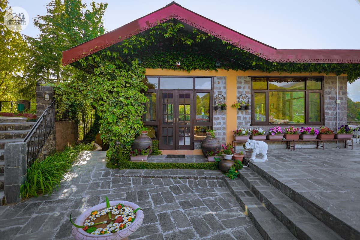 Stone-and-slate main building with ivy-covered front at Udechee Huts, Naddi