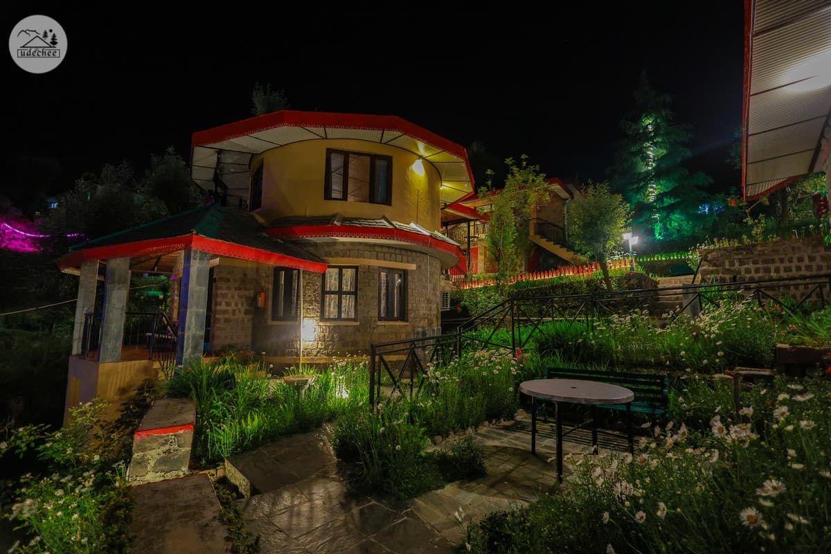 Cottages and garden lit up at night at Udechee Huts, Naddi