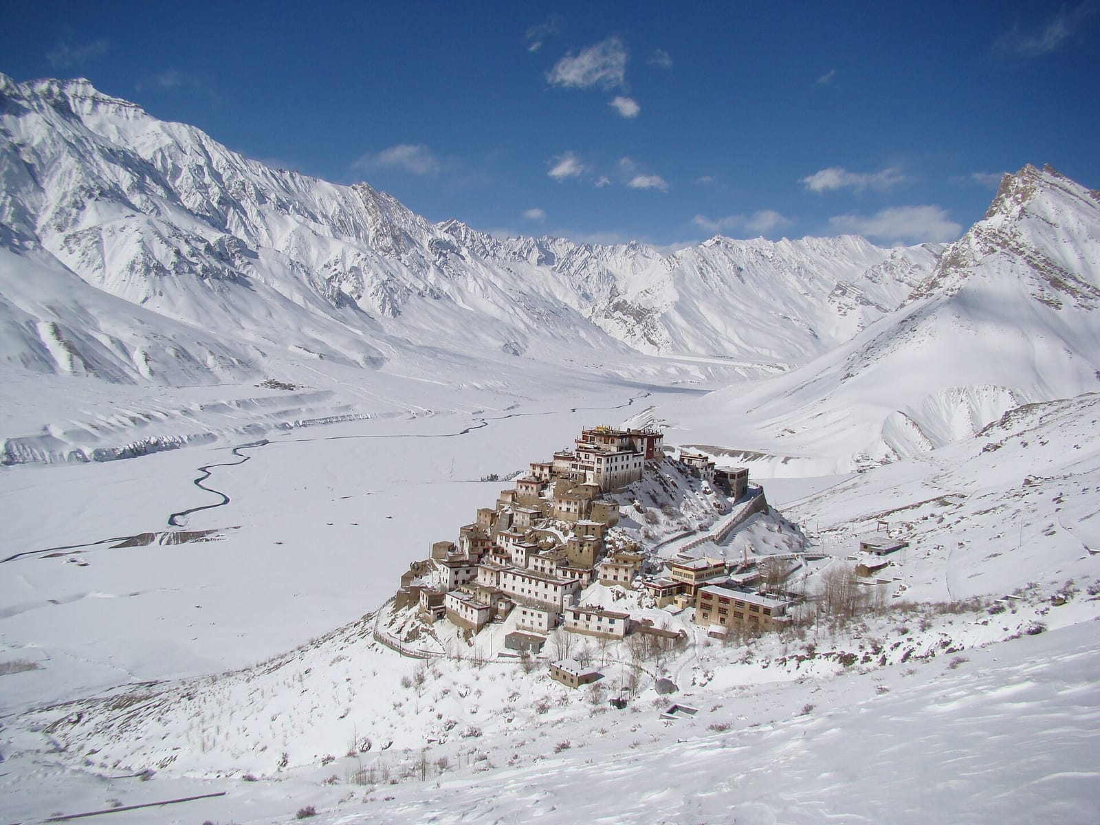 Key Monastery on its hilltop above the snow-covered Spiti valley in winter, with white mountains and blue sky