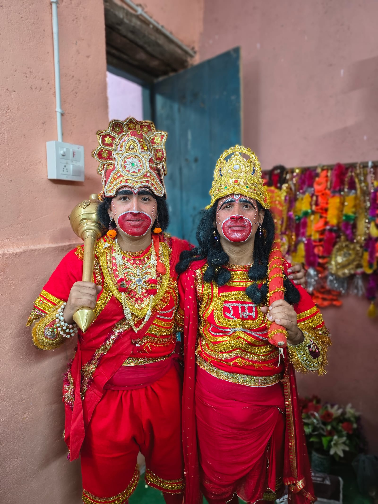 Two Ramlila actors in costume as Hanuman and Angad holding maces backstage at a village Ramlila